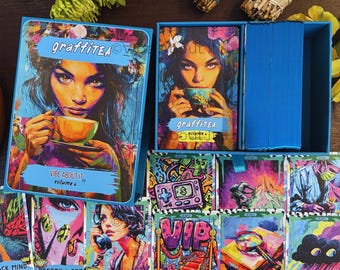 May include: A deck of Graffitea Volume 4 oracle cards in a blue box, featuring a colorful illustration of a person holding a teacup. The set includes a stack of cards and several individual cards displayed below, each with vibrant graffiti-style artwork and titles like Unsecured Line, Vip Treatment, Gumshoe, and Black Cloud.