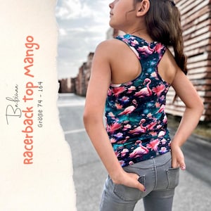 May include: A racerback tank top featuring a dark teal background with a repeating pattern of pink flamingos and lotus flowers. The text on the side reads Babinaa racerback top mango Größe 74 - 164. The garment is paired with gray denim jeans.