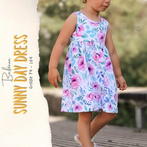 Op de afbeelding: Een mouwloze jurk met een witte basis en een bloemenpatroon van roze rozen en blauwe bladeren. De tekst aan de zijkant luidt Babinaa SUNNY DAY DRESS GRÖBE 74 - 164. De jurk heeft een ronde halslijn en een geplooide taille met een uitlopende rok.