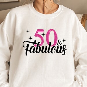 May include: White sweatshirt with a pink glitter design that says "50 & Fabulous".