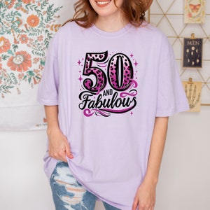 May include: A lavender t-shirt with a pink and black leopard print design that says "50 and Fabulous".