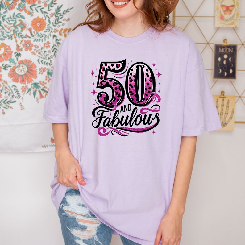 May include: A lavender t-shirt with a pink and black leopard print design that says "50 and Fabulous".