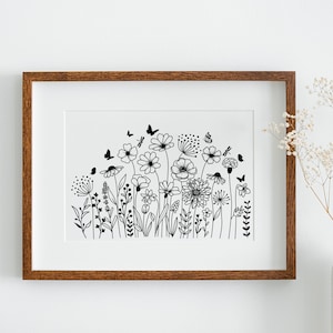 Op de afbeelding: Een zwart-witte lijntekening van een veld met wilde bloemen en vlinders. De tekening is ingelijst in een bruin houten lijst.