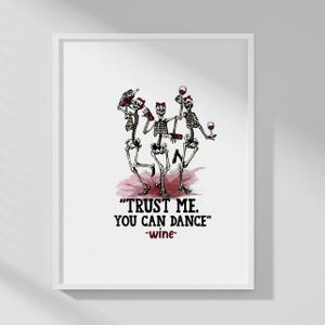 Peut inclure: Une affiche encadr&eacute;e repr&eacute;sentant trois squelettes dansant avec des bouteilles et des verres de vin sur une tache bordeaux. Le texte "TRUST ME. YOU CAN DANCE" est affich&eacute; en dessous, avec "-wine-" en dessous.