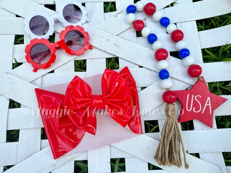 May include: Red, white, and blue beaded garland with a wooden star that says "USA" and a red patent leather bow.