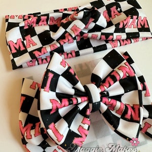 May include: A black and white checkered headband and bow with the word "Mama" in pink letters. The headband and bow are handmade and have a glittery finish.
