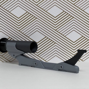 Op de afbeelding: Een 3D-geprint model van een futuristisch ruimteschip in grijs en zwart met een lang, dun lichaam en een puntige neus. Het ruimteschip heeft een kleine, ronde motor aan de achterkant en een vleugelachtige structuur aan de zijkant.