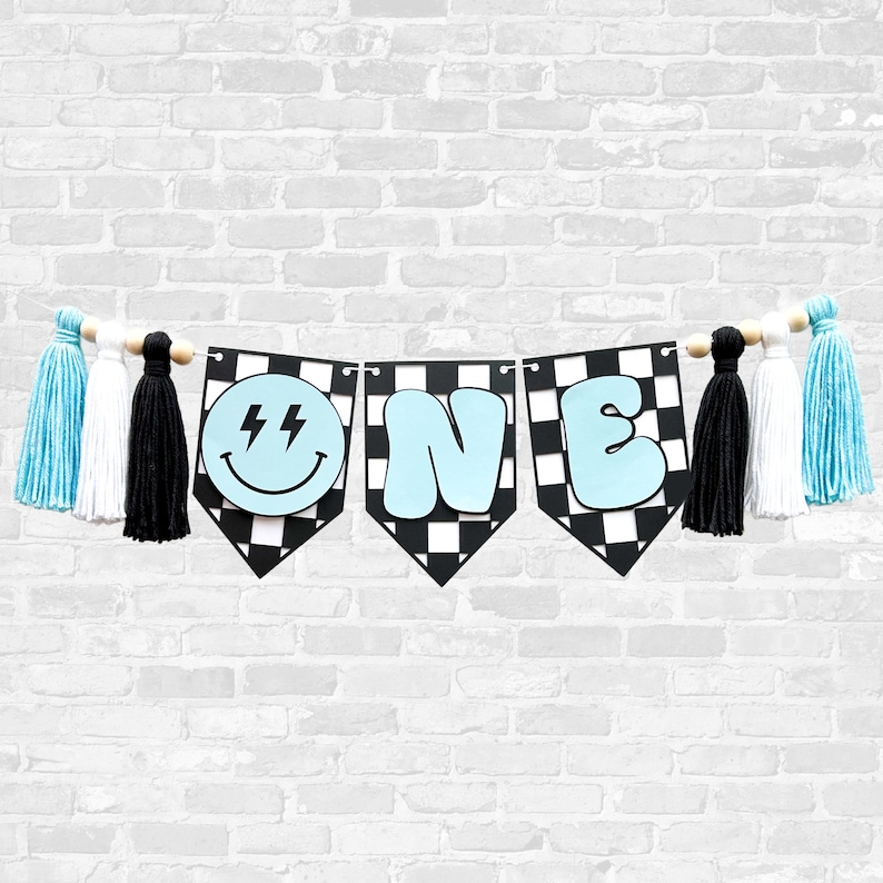 May include: A blue and black checkered banner with the word "ONE" in blue letters and a smiley face with lightning bolts. The banner is decorated with blue, white, and black tassels.