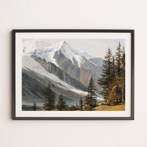 May include: A framed painting depicting a snow-capped mountain range with a forest in the foreground. The mountains are a light grey with a white snow cap. The forest is a dark green with a few brown trees. The painting is framed in a dark grey frame.