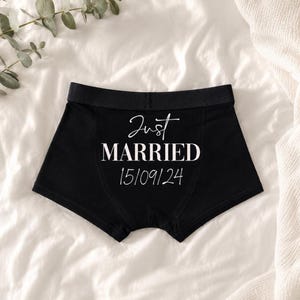 May include: Black boxer briefs featuring the white text Just MARRIED and the date 15/09/24 printed on the front. The garment has a solid black waistband and a fitted silhouette, presented as a clean and simple piece of apparel.