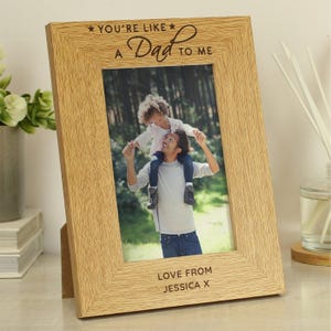 May include: A light oak picture frame with the text "YOU'RE LIKE A Dad TO ME" and "LOVE FROM JESSICA X". The frame contains a photo of a person with a child on their shoulders.