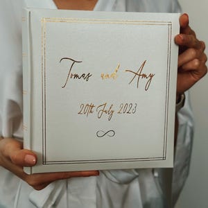 White leather photo album for wedding photographs. The album has a gold lining on the from cover and the personalisation is in matching gold colour. You can include your names and wedding date. Slip in album for 200 photos, size 4 x 6 inch,10 x 15 cm