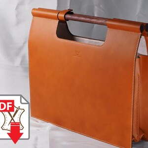 May include: A tan leather tote bag with a rectangular shape and a wooden handle. The bag features white stitching along the edges and a small logo on the front. The bag is designed to carry documents or other items.