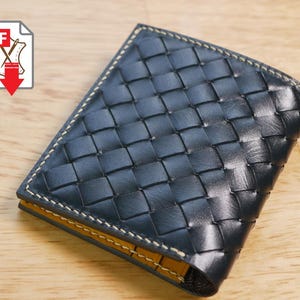 Op de afbeelding: Een donkerblauwe leren portemonnee met een geweven patroon. De portemonnee heeft een gele binnenkant en witte stiksels langs de randen. Een PDF-pictogram met een leersymbool en een rode pijl staat linksboven.