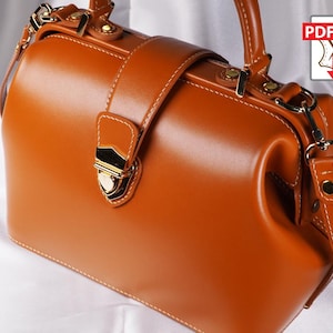 May include: A structured, caramel-colored leather handbag with a top handle and a detachable shoulder strap. The bag features gold-toned hardware, including a clasp closure and decorative accents. White stitching outlines the bag's panels. The image includes a PDF icon.