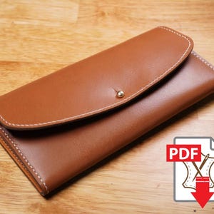 May include: A tan leather wallet with white stitching and a silver stud closure. The wallet is rectangular with a curved flap. The image includes a PDF icon with a leather sewing graphic and a red arrow.