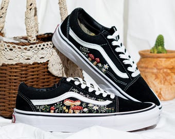 Puede incluir: Zapatillas negras y blancas con diseños bordados de setas y flores. Los zapatos tienen cordones blancos, suela blanca y el texto "Mrs. Bright" en el lateral. Se muestran sobre una superficie blanca.