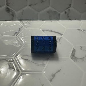 Può includere: Un puzzle di numeri blu e nero con i numeri 5, 0, 4, 6, 1, 5, 7, 2 e 6 visibili sui lati.