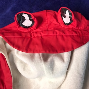 May include: Red hooded jacket with white fleece lining and frog ears on the hood.