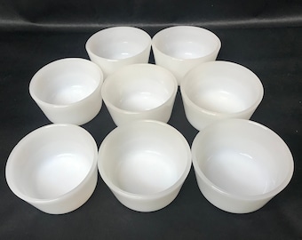 May include: Set of eight white ceramic bowls. The bowls are round and have a smooth, glossy finish.