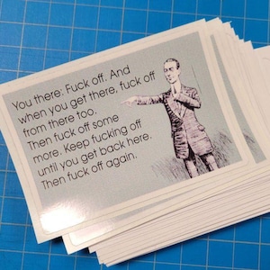 May include: A pile of white cards with a light blue border, featuring the text "You there: Fuck off..." and a vintage illustration of a man in a suit. The cards are on a blue grid surface.