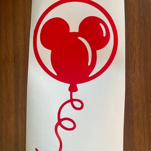 May include: A red Mickey Mouse balloon sticker on a white background. The balloon is inside a red circle and has a curly red string. The sticker is on a white background.