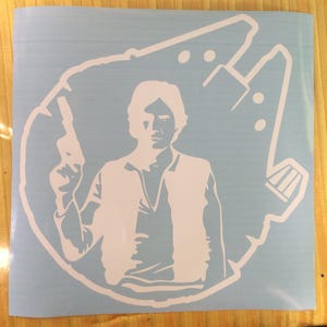 Può includere: Adesivo in vinile bianco raffigurante Han Solo con un blaster, ambientato sul contorno del Millennium Falcon. Il design è su sfondo azzurro chiaro, adatto a varie superfici.