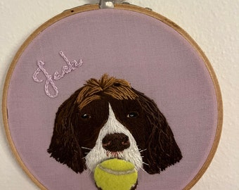May include: Embroidered portrait of a brown and white dog with a yellow tennis ball in its mouth. The dog's name, "Jack", is embroidered above the portrait on a light purple fabric background.