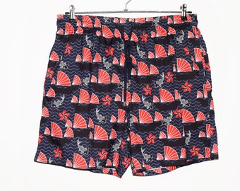May include: Blue swim trunks with a red and white patterned design featuring fans, flowers, and fish.