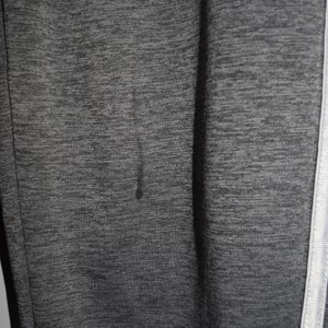 Puede incluir: Primer plano de una tela texturizada gris y negra con una franja blanca a lo largo del lado.