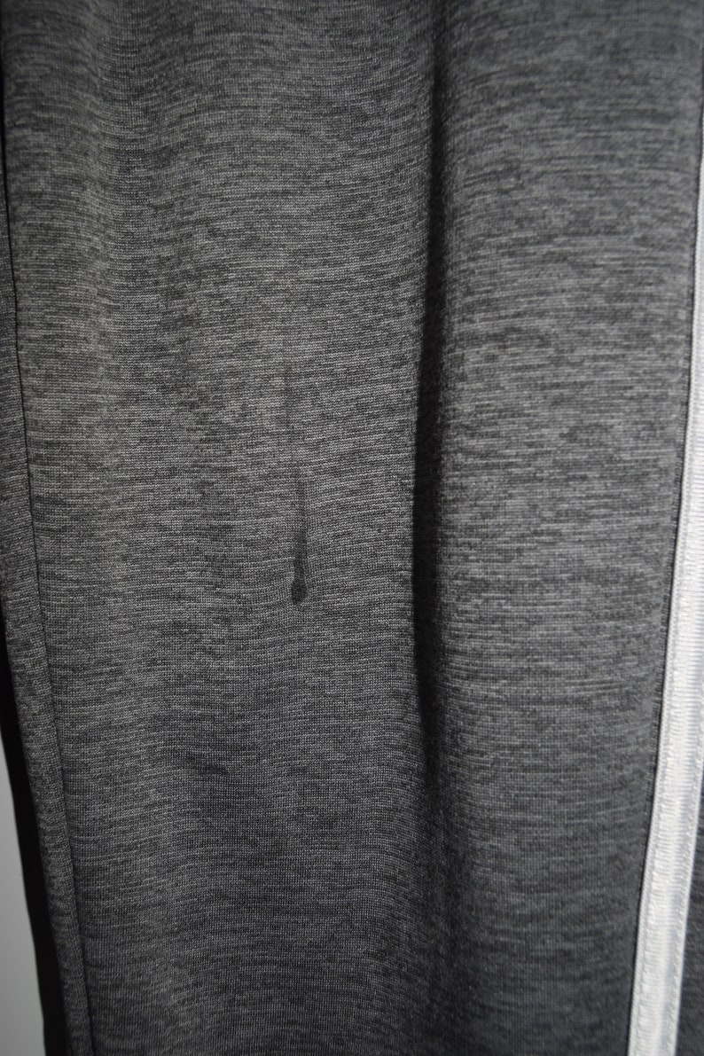 Puede incluir: Primer plano de una tela texturizada gris y negra con una franja blanca a lo largo del lado.