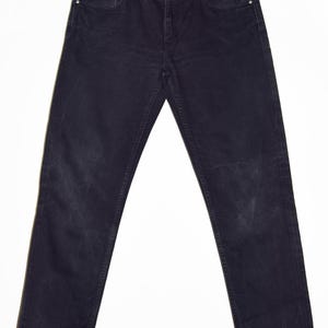 May include: Dark wash denim jeans hanging on a metal hanger. The jeans have a classic five-pocket design, a button and zipper closure, and a straight leg fit. The denim appears to be pre-worn, with some fading and wear marks.
