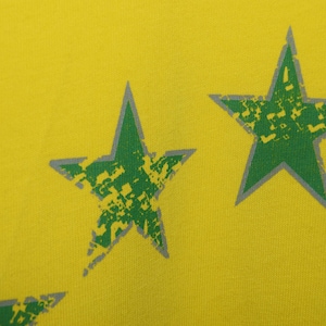 May include: Yellow fabric with a green and gray star pattern.