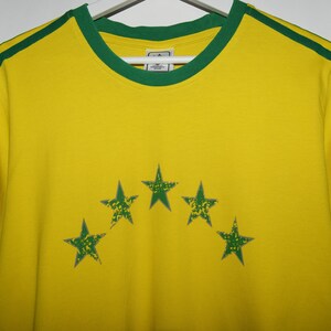 May include: Yellow t-shirt with green trim and five green stars in an arc on the front.