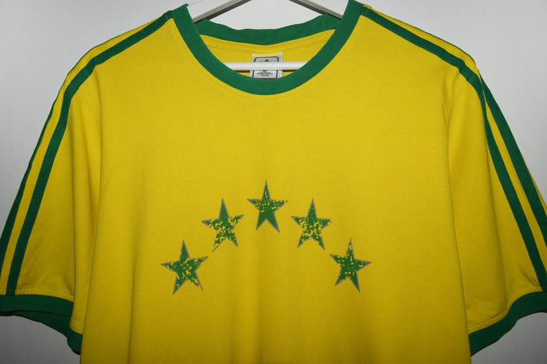 May include: Yellow t-shirt with green trim and five green stars in an arc on the front.