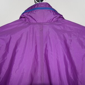 May include: A purple nylon jacket with a blue zipper and a hood.