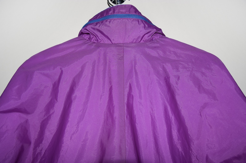 May include: A purple nylon jacket with a blue zipper and a hood.
