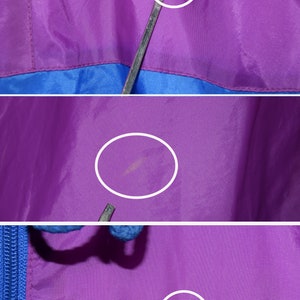 May include: Close-up of a purple and blue jacket with a zipper. The jacket has a few small marks on the purple fabric.