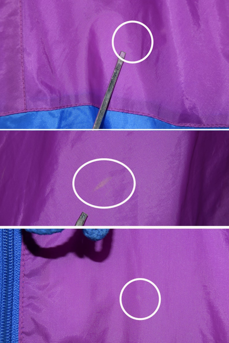 May include: Close-up of a purple and blue jacket with a zipper. The jacket has a few small marks on the purple fabric.