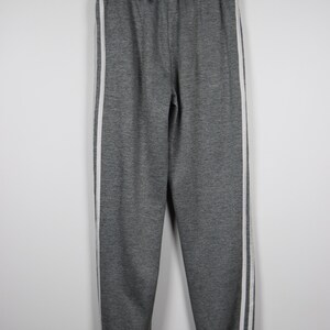 Puede incluir: Pantal&oacute;n de ch&aacute;ndal gris con rayas blancas a los lados. El pantal&oacute;n de ch&aacute;ndal tiene una cintura con cord&oacute;n y un dobladillo en la parte inferior.