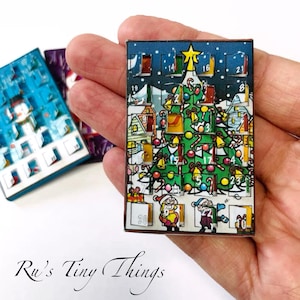 May include: A miniature Christmas advent calendar with a festive design. The calendar features a Christmas tree with ornaments, presents, and a star on top. The numbers 1 through 24 are visible on the calendar.