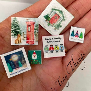 May include: Miniature Christmas-themed cards with various designs, including a red postbox, a dog in the snow, a house with a red door, Christmas trees, and Santa Claus. The cards have the text "Merry Christmas" and "Have a wolly Christmas".