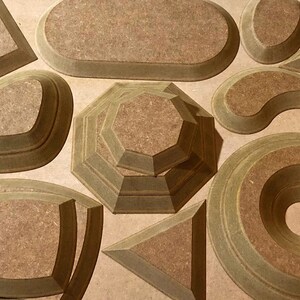 May include: A set of 10 wooden geometric shapes, each with a layered design. The shapes are in various sizes and include a square, oval, circle, diamond, and more. The shapes are made of a light brown wood with a natural finish.
