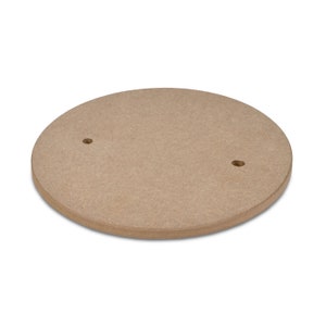 Op de afbeelding: Een ronde, lichtbruine houten schijf met twee geboorde gaten. De schijf heeft een diameter van ongeveer 30 cm.