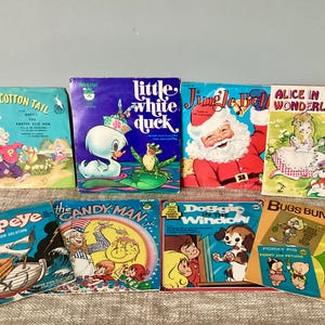 May include: A collection of vintage children's books and records featuring colorful illustrations. Titles include "Peter Cotton Tail," "Little White Duck," "Jingle Bell," "Alice in Wonderland," "Popeye," "The Candy Man," "Doggie Window," and "Bugs Bunny."