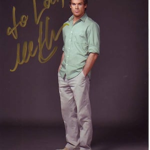 May include: A man wearing a light green button-down shirt and beige pants. He is standing with his hands in his pockets. The man is smiling and looking at the camera. The image is signed "To Loui, with love".