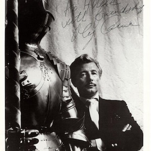 Puede incluir: Fotografía en blanco y negro que presenta a un hombre con traje y corbata, junto a una armadura. La imagen incluye texto manuscrito que dice "To Adele with friendship, Guy Green."