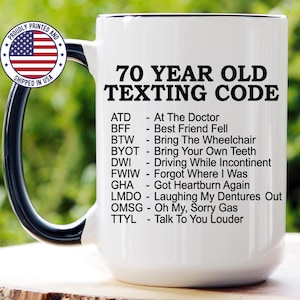 May include: A white 15 oz ceramic mug with a black handle and interior. The mug features the black text 70 YEAR OLD TEXTING CODE followed by a list of humorous acronyms and their meanings, including ATD, BFF, BTW, BYOT, DWI, FWIW, GHA, LMDO, OMSG, and TTYL.