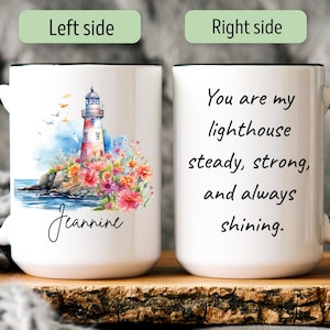 May include: White ceramic mug with a black handle and rim. The left side features a watercolor illustration of a lighthouse with colorful flowers. The right side has the text "You are my lighthouse, steady, strong, and always shining."