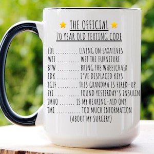 May include: White ceramic mug with a black handle and rim, featuring the text "THE OFFICIAL 70 YEAR OLD TEXTING CODE" and a list of humorous acronyms. The mug holds 15 oz.